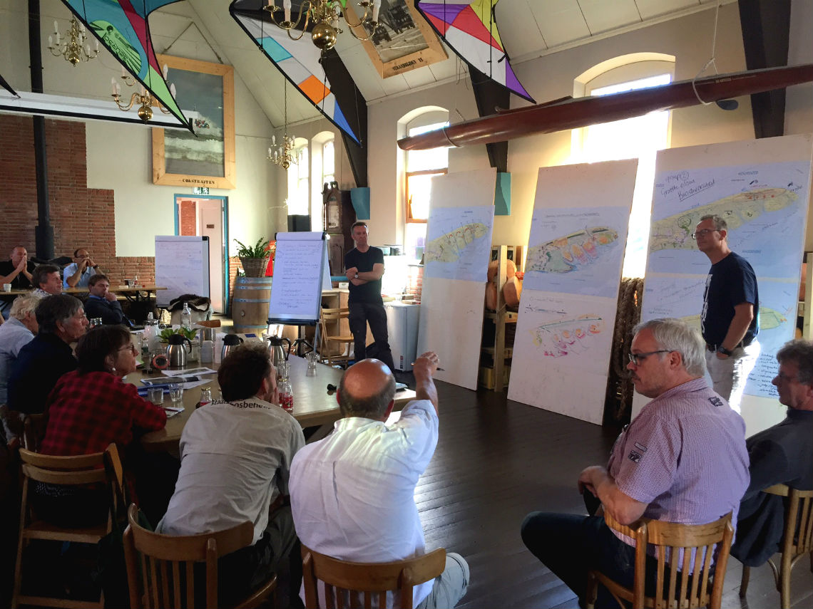 Peter de Ruyter staat voor een groep toehoorders over plannen voor de Boschplaat op Terschelling.