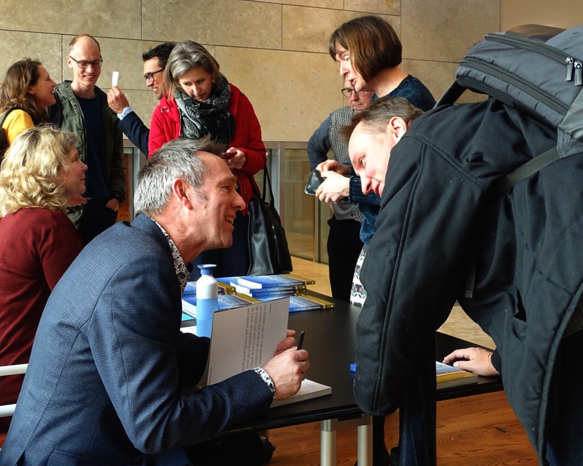 Peter de Ruyter signeert de tweede druk van zijn boek "Vloeiend Landschap" bij het centraal bureau voor de leefomgeving in Den Haag.